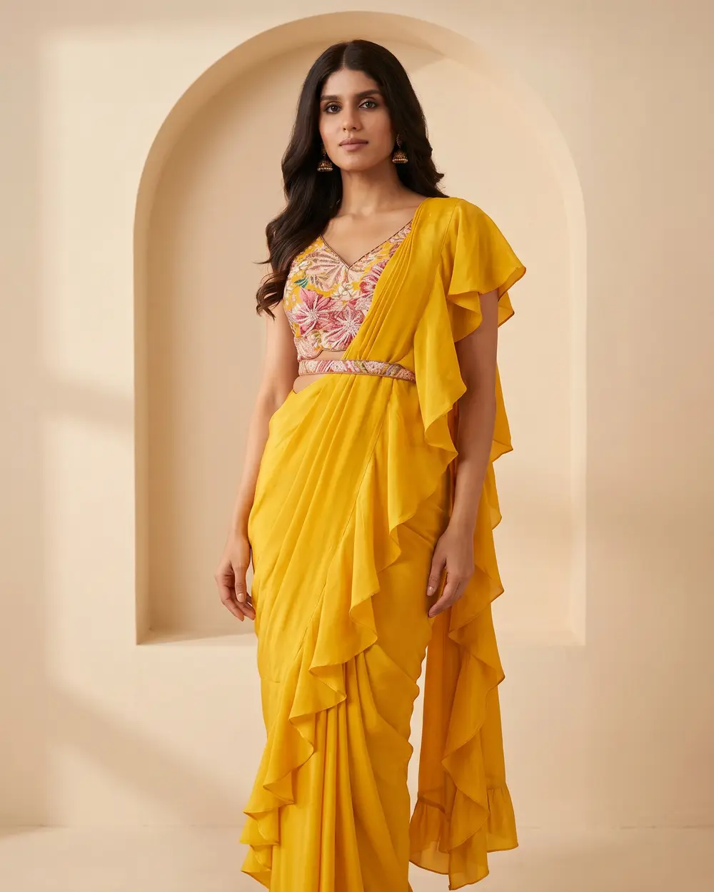 Model in a mustard-yellow pre-draped ruffle saree with an embroidered blouse and belt